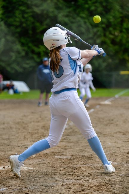 Youth softball player making contact mid-swing during a game