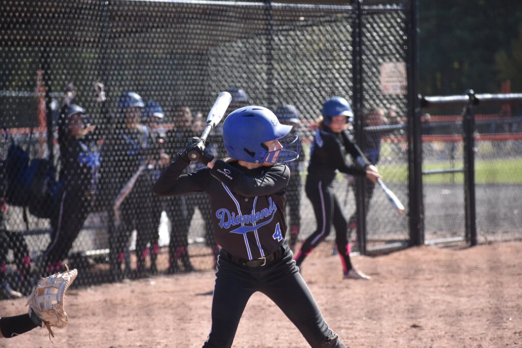 Diamond Softball Club player warming up on deck during a game, in team uniform