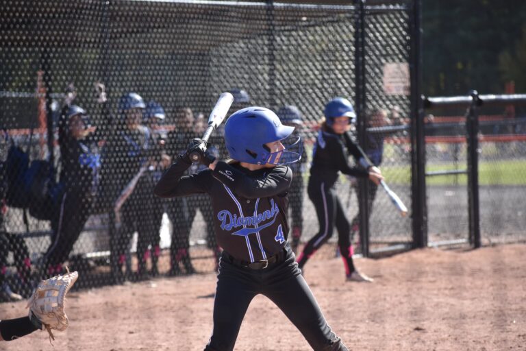 Diamond Softball Club player warming up on deck during a game, in team uniform