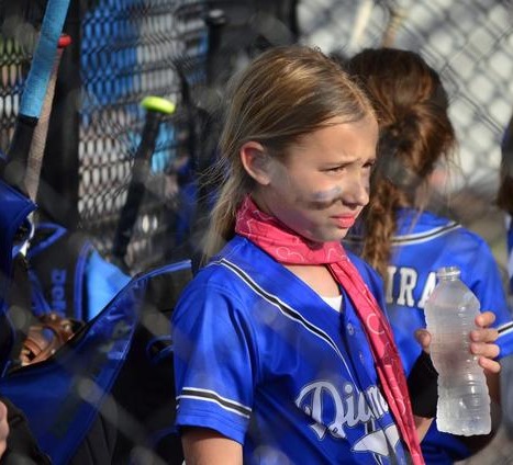Diamond Softball Club player holding a water bottle in the dugout during a tournament day