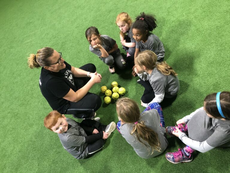 Diamond Softball Club coach sitting in a circle with a small group of Little Gems feeder-program players